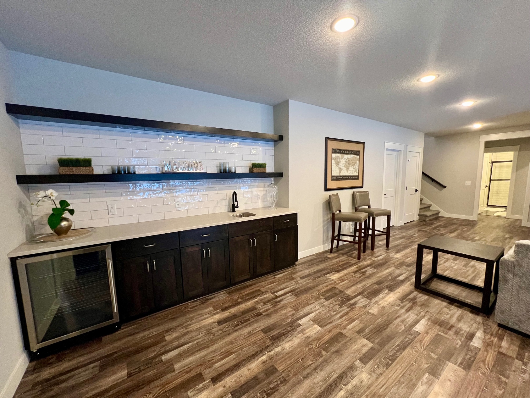 Quartz counter, subway tile, beverage fridge, and floating shelves.
