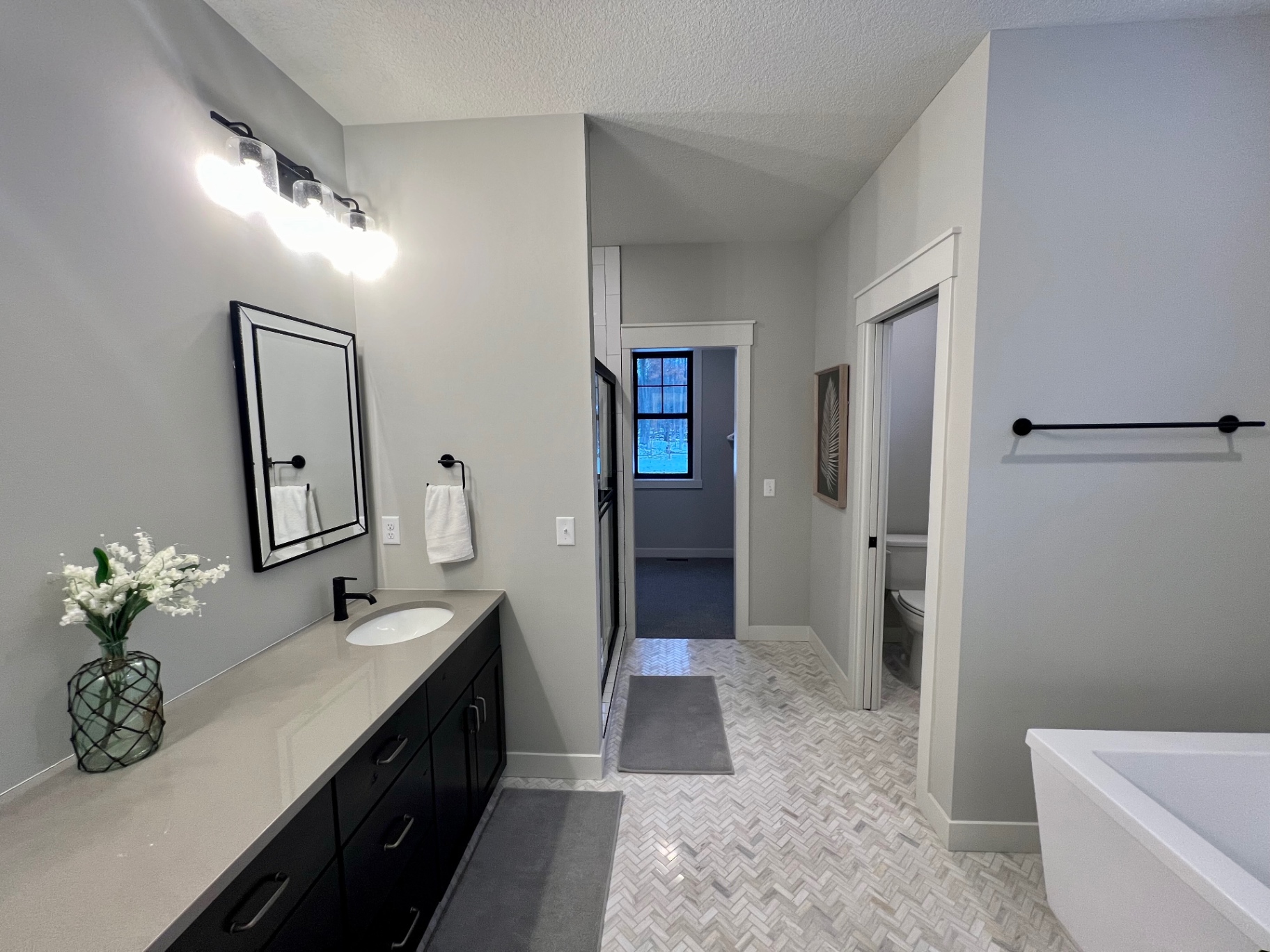 Long double vanity, soaking tub, and patterned tile floor.