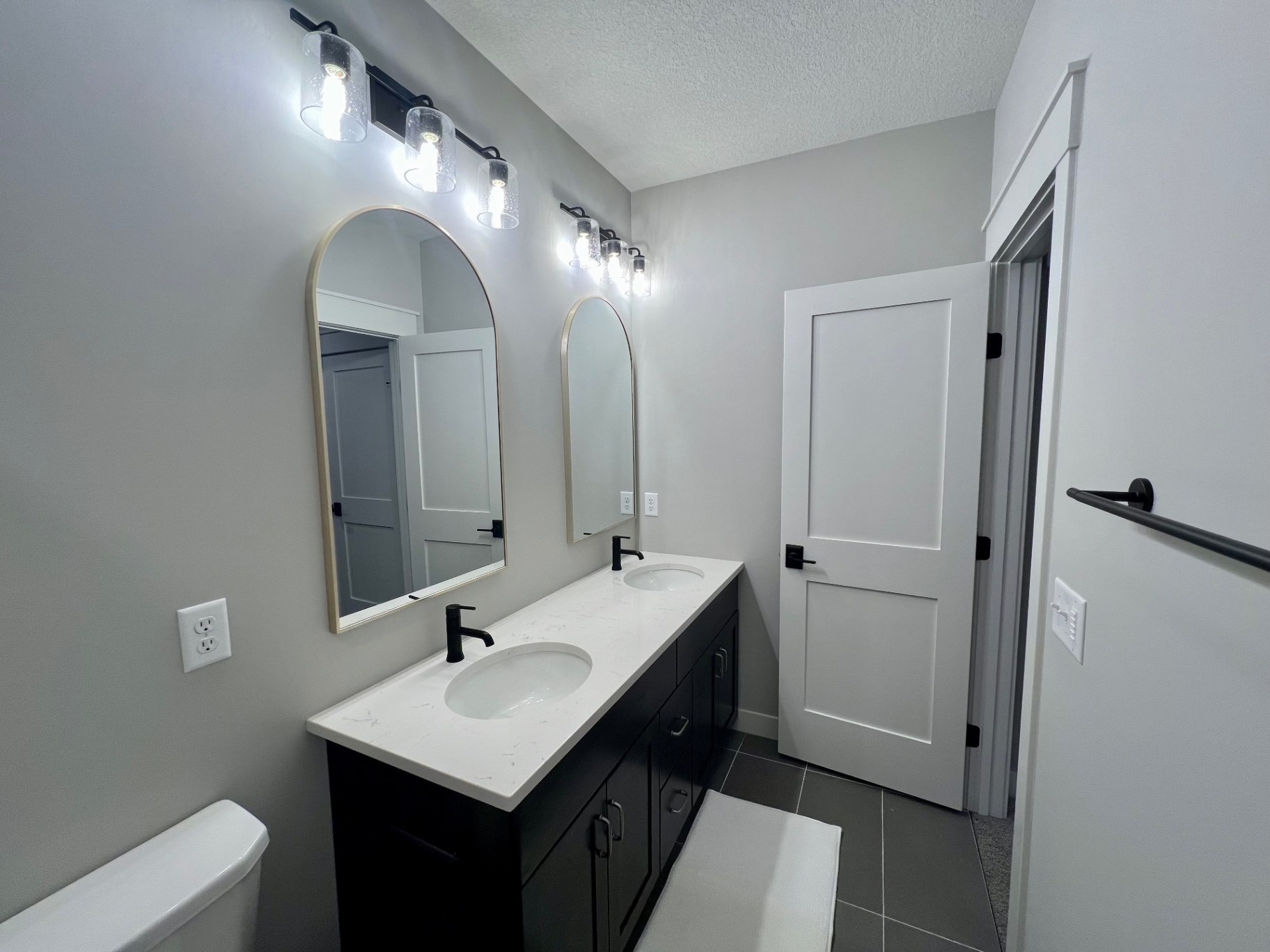 Shower bath with dual mirrors and dark cabinetry.