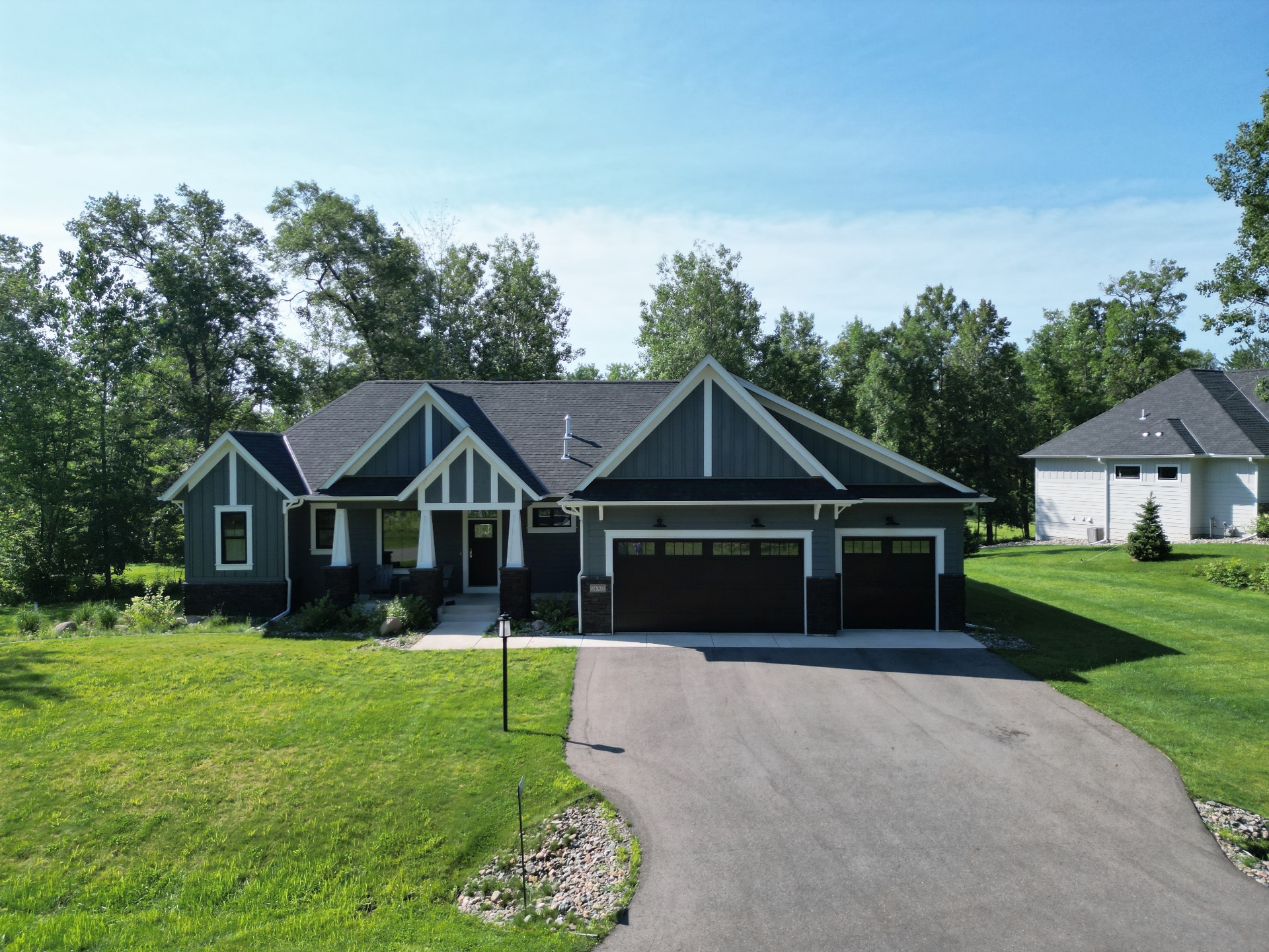 Board-and-batten gables, timber brackets, and a covered front porch framed by the pines.