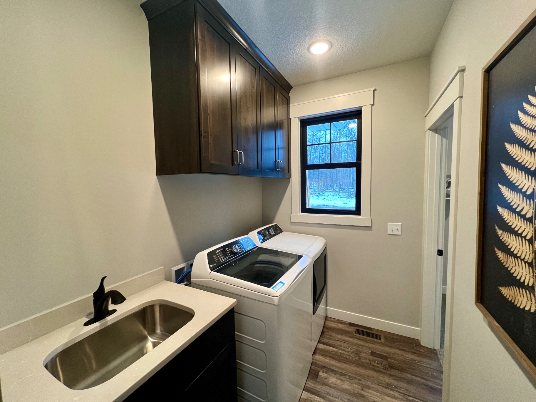 Quartz folding counter with stainless utility sink and top-load washer/dryer.