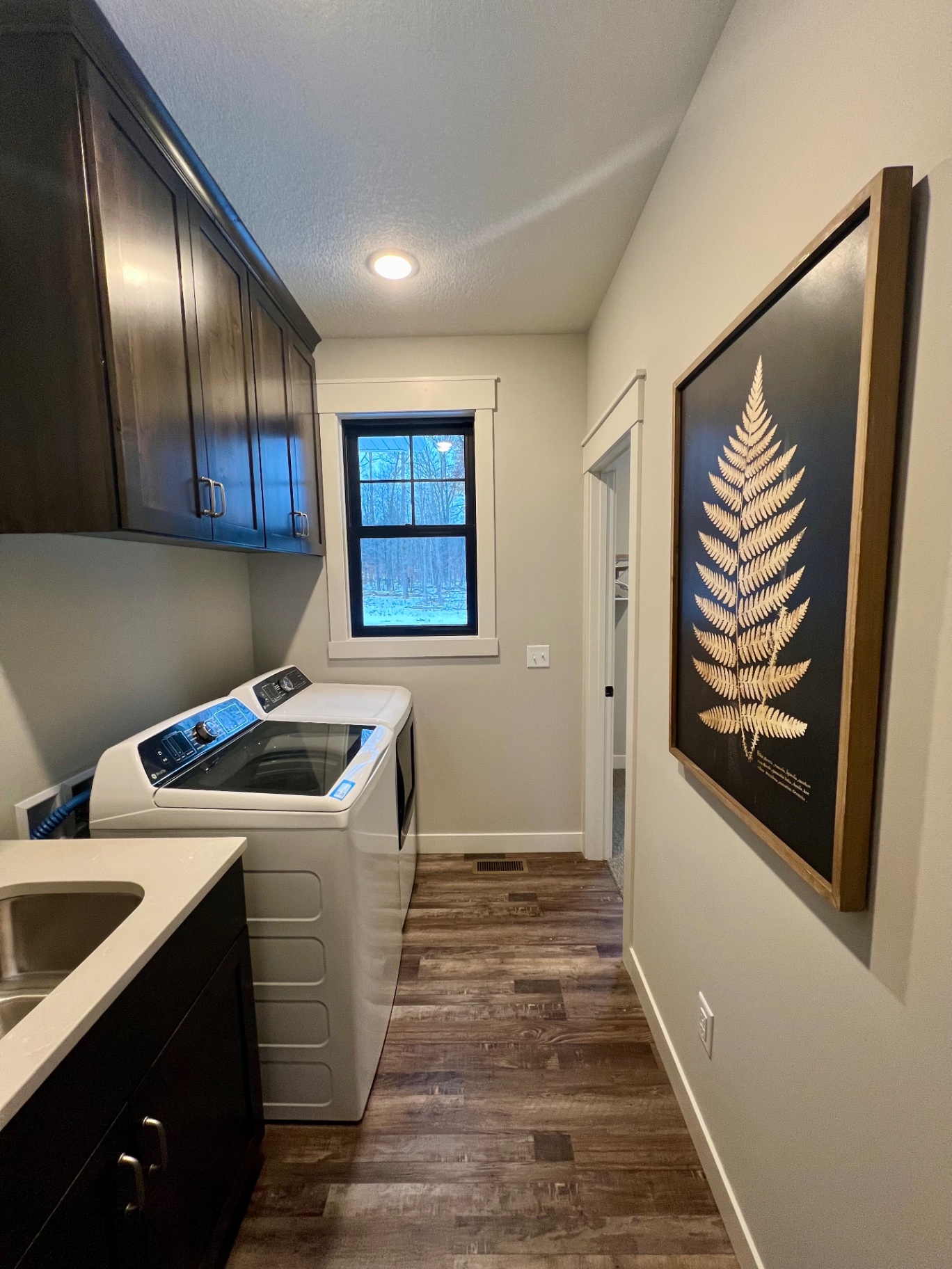 Wood floors, dark cabinets, and a framed botanical down the hall.