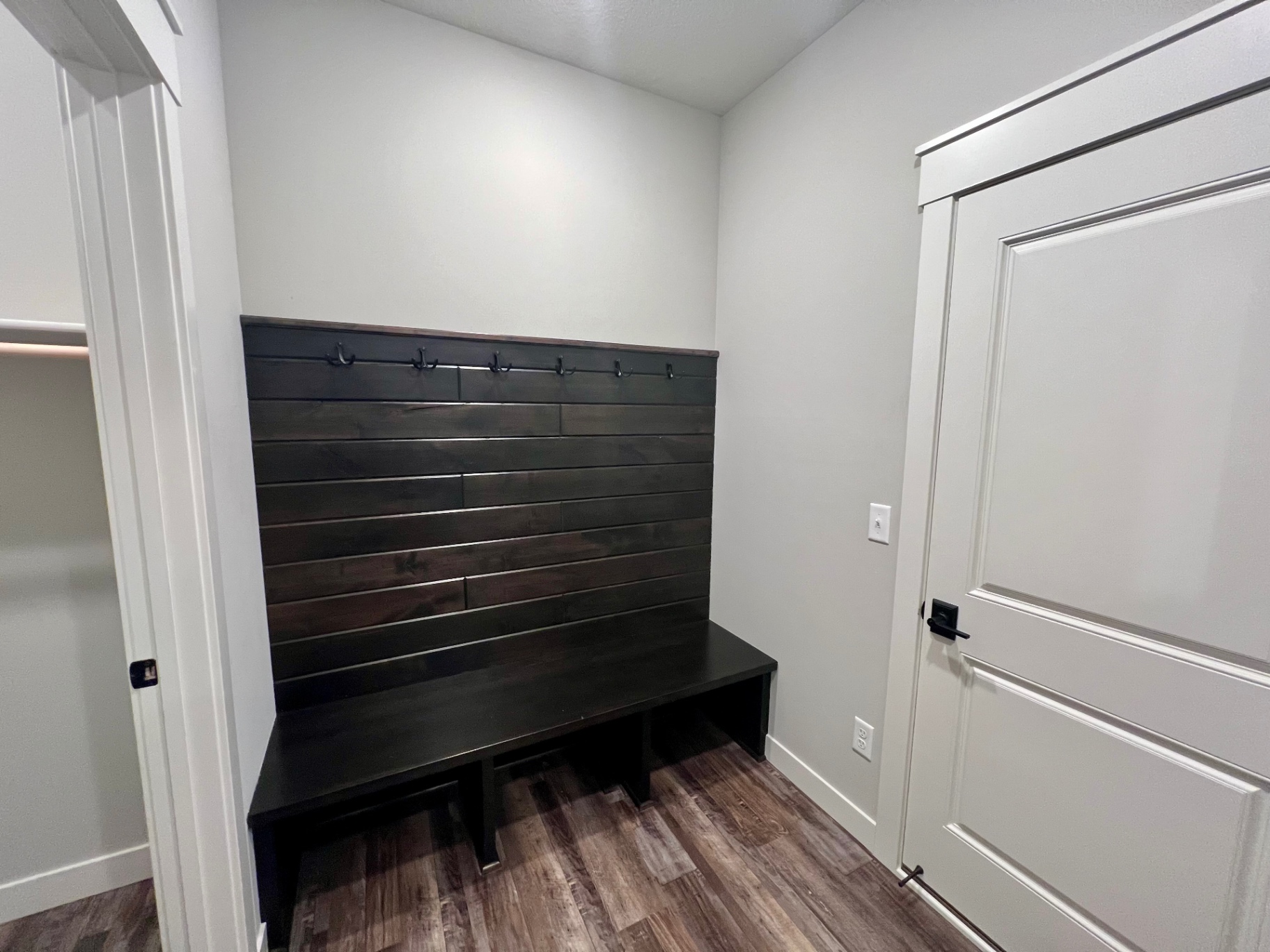 Shiplap bench with hooks at the garage entry — boots, bags, and golf gear sorted.