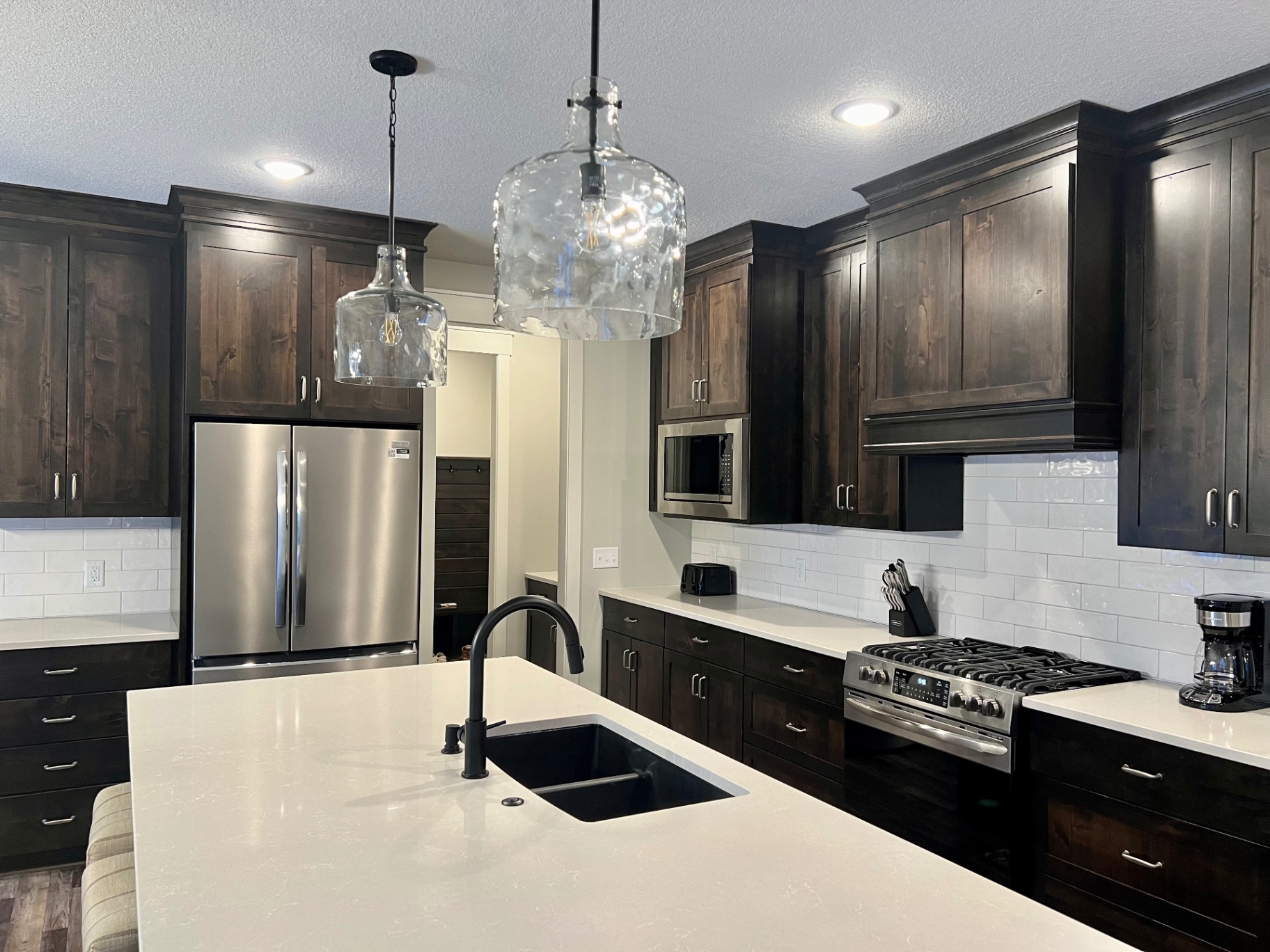 Five-burner gas range, subway tile, and a deep matte-black undermount sink.