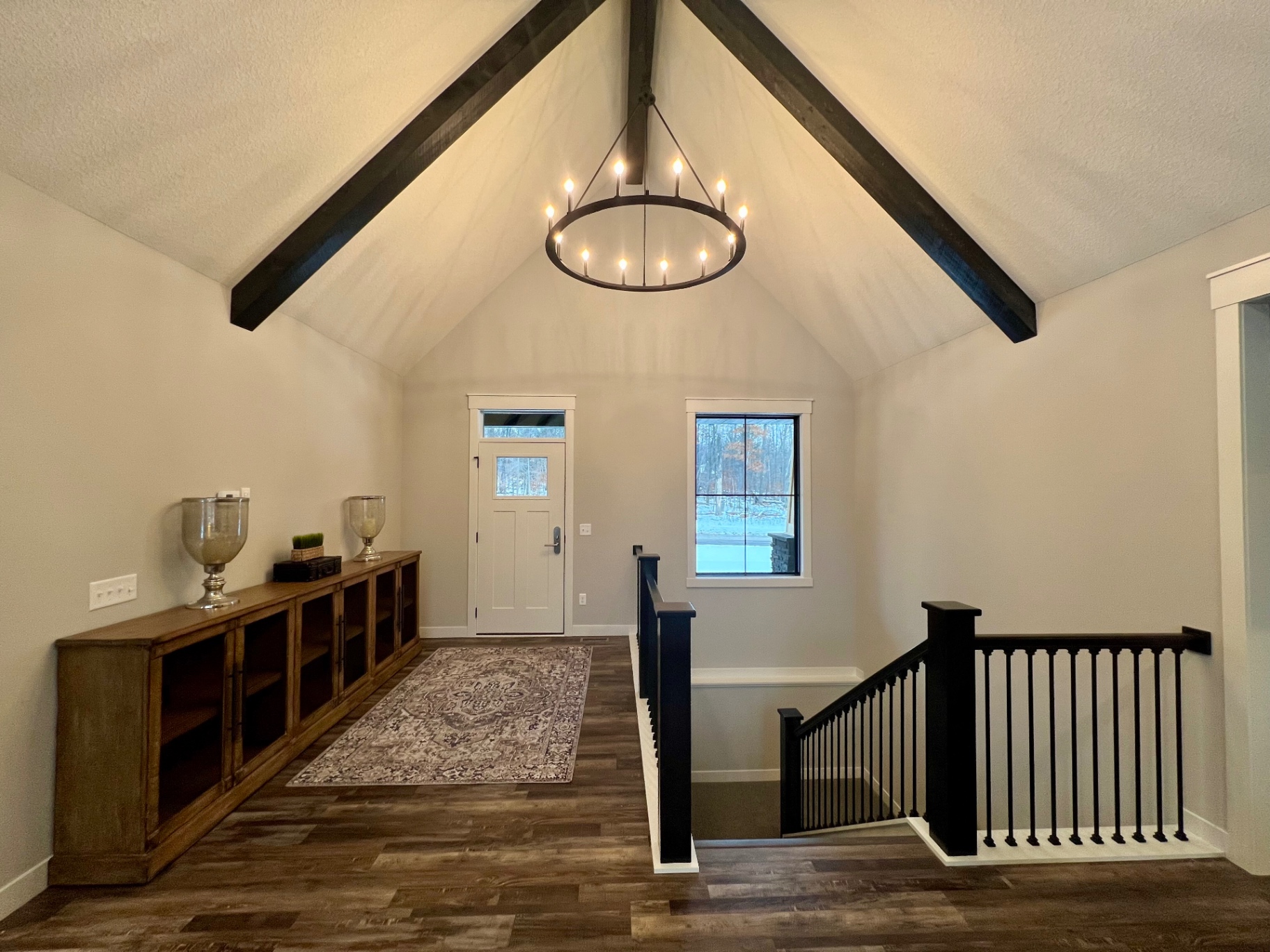 Cathedral ceiling with timber beams and ring chandelier above the foyer.