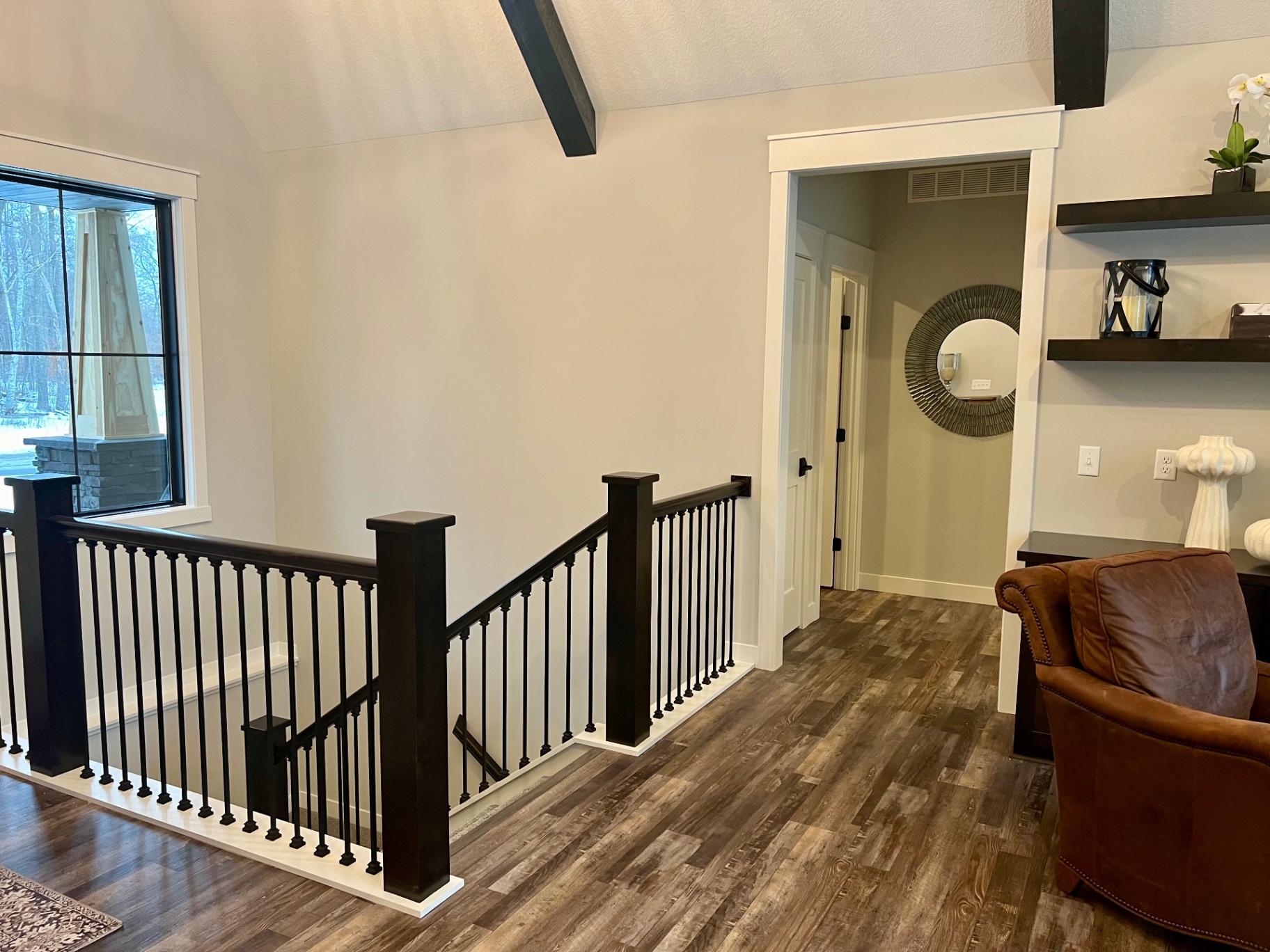 Floating shelves and a leather chair beside the stair rail.